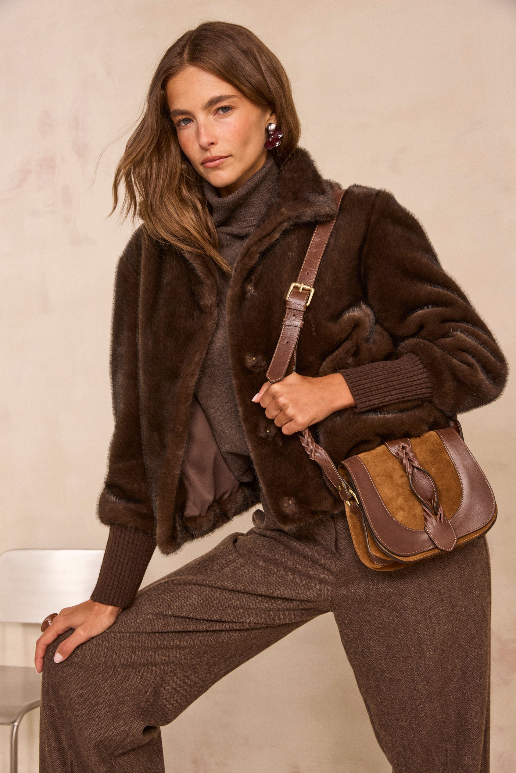 Femme portant un blouson en fausse fourrure marron foncé et un sac en cuir camel
