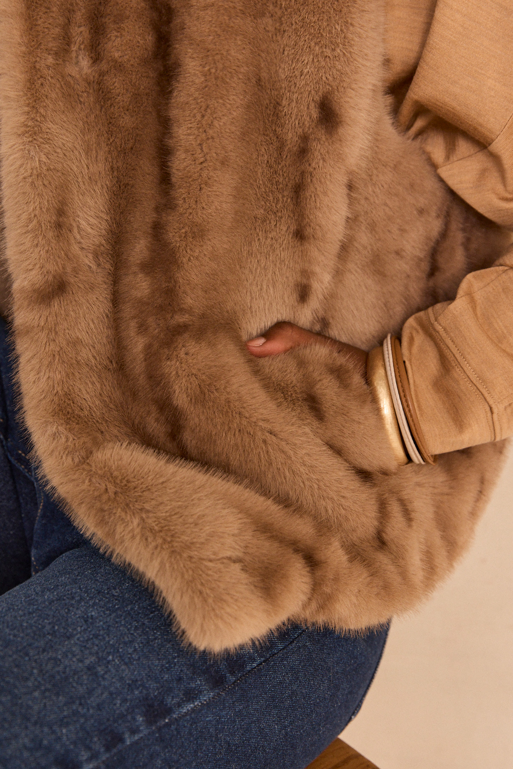 Détail d'une veste en fausse fourrure camel, main dans la poche